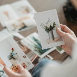 crop photographer choosing photos of flowers at table